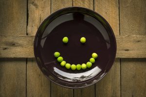 Peas, that are high in nutrition, in a pan in the shape of a smiling face