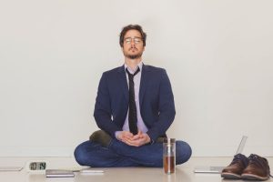 Man in a suit in a meditation pose trying to be calm