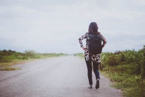 Woman with a backpack walking on a road moving forward