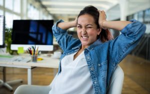 Woman sitting at her desk holding her head frustrated with her workplace problems